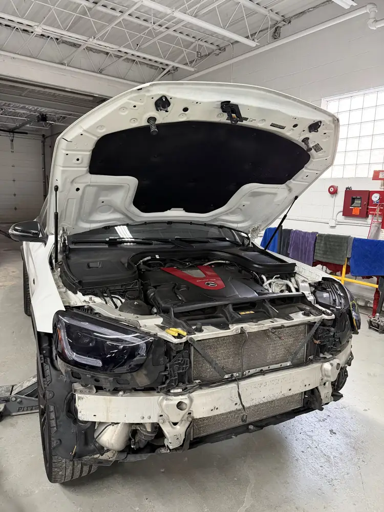 White Mercedes with the front bumper off for grille work