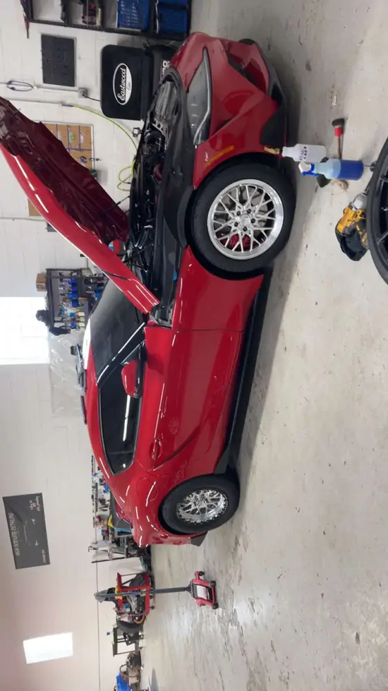 Red sports car in the bay with a wheel off for service